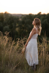 Fototapeta na wymiar Young pretty woman in dress outdoors posing in a field