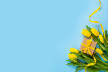 Yellow tulip flowers and gift box on blue background. Women's day or Mother's day concept. Flat lay, top view