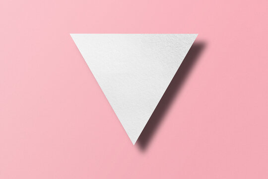 White paper cut into triangle shape, play button set on pink paper background.