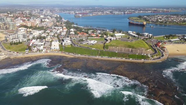 Aerial drone view of the harbour city of Newcastle, NSW, Australia as a cargo ship enters Newcastle Harbour on a sunny day 
