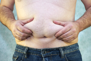 a man in jeans with a bare torso and a small belly close-up of the concept of overweight body positive