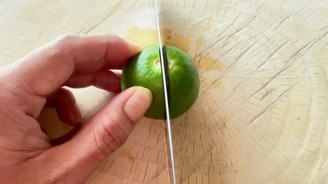 to cut lemon with knife on a wooden cutting board 
