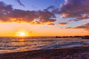 empty beach with surf during beautiful sunrise or sunset with surf, clouds and golden sun