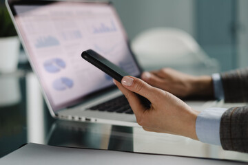Image of female hands using mobile phone app for synchronizing data with netbook via bluetooth.