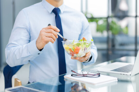 Unrecognizable businessman eating a vegetables salad for lunch, healthy and lifestyle concept.