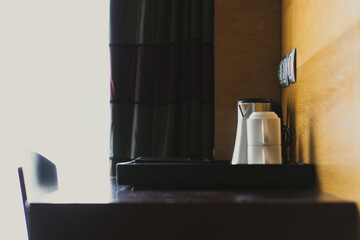 white cups and a coffee pot on top of a tray on a brown wooden table