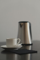 a white cup with a coffee pot on a black wooden table