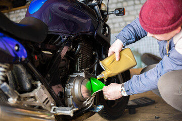 Obraz premium pouring new engine oil into a motorcycle engine.