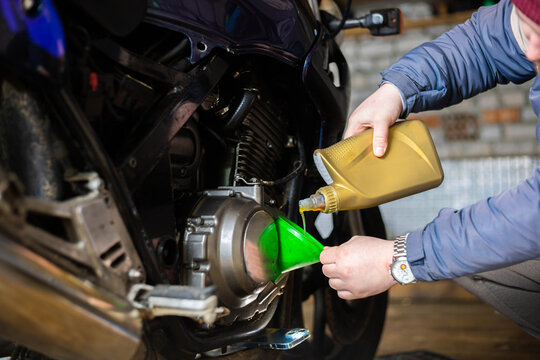 pouring new engine oil into a motorcycle engine.