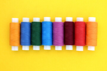  Background of multi-colored bright threads lying on a yellow background.