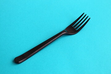 A black fork lies on a turquoise background.