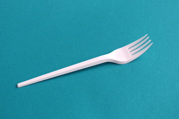 On a turquoise background lies a white fork.