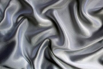 Gray satin fabric lies drapery, top view.