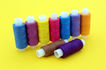  On a yellow background there are many bright multi-colored threads for sewing.