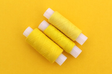 Fototapeta na wymiar Several spools of yellow thread lie on a yellow background.