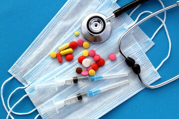 Against the background of the masks are pills and a stethoscope.
