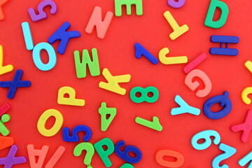 Background of bright multi-colored plastic letters lying on a red background.