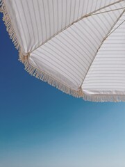 Striped beach umbrella over blue sky