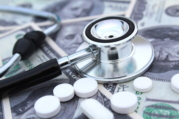 On dollar money are medicine pills and a stethoscope for diagnosis.