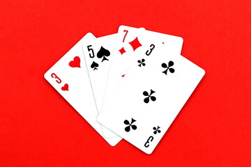 Playing cards in a pile lie on a red background.