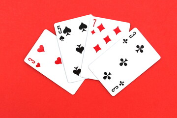 Playing cards in a pile lie on a red background.