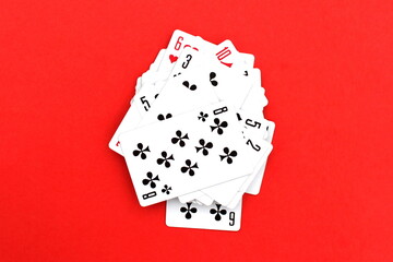 Playing cards in a pile lie on a red background.