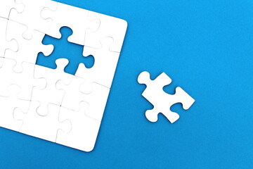 The game, a lot of white puzzle pieces lie on a blue background.