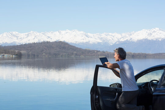 Mature man take photo of lake with tablet
