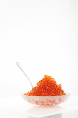 Red caviar.Red caviar in a transparent dish in the form of a shell on a white background. Vertical photo.Copy space.
