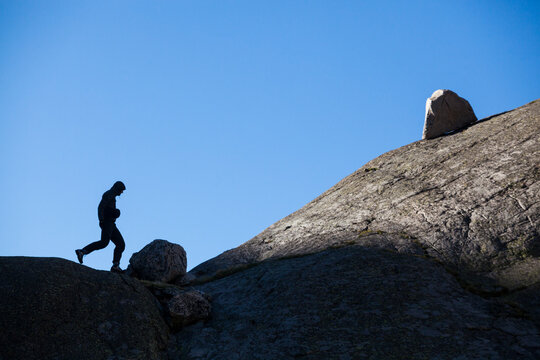 A young man runs among glacial erratics above Spectacle Lakes, Rocky Mountain National Park, Colorado.