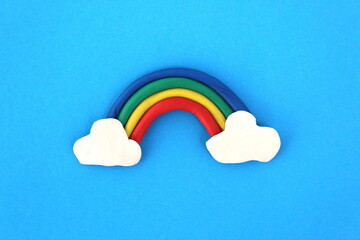  A rainbow molded from plasticine lies on a blue background.