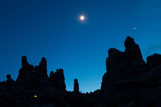 A tent glows at night below the sandstone towers of The Doll House in Canyonlands National Park, Utah.