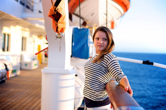 Young woman leaning against railing on deck of cruise ship, Bahamas