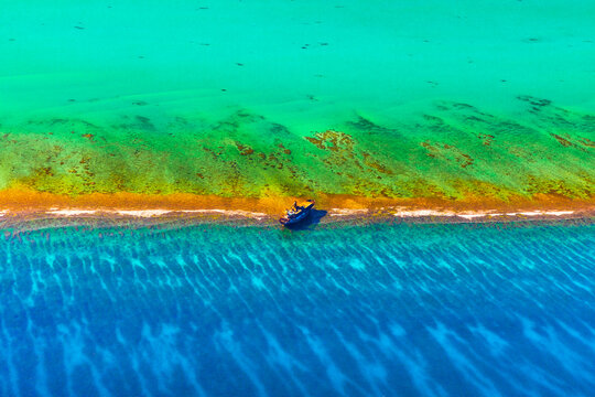 Lone abandoned ship on border of sea and lagoon