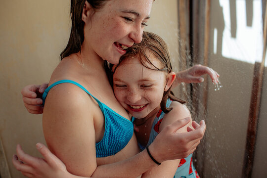 Sisters hugging in outdoor shower after swimming