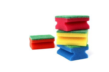 Many bright multi-colored sponges for washing dishes lie on a white background.	