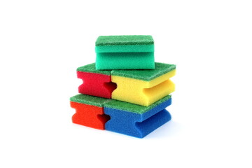 Many bright multi-colored sponges for washing dishes lie on a white background.