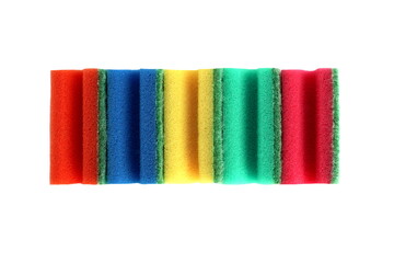 Many bright multi-colored sponges for washing dishes lie on a white background.
