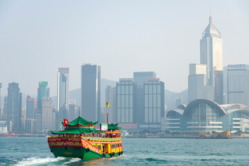 Hongkonese junkboat sailing across Victoria Harbour toward Hong Kong skyline- stock photo