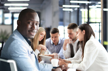 Portrait of smiling African American business man with executives working in background