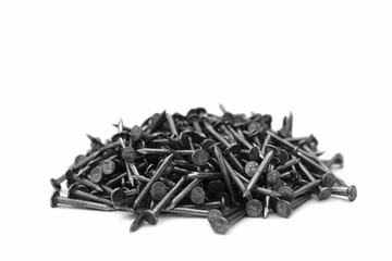 A pile of large iron nails lie on a white background	