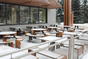 The tables at the cafe on the street are covered with snow in winter.