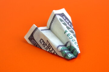 On a bright background lies a homemade plane made from dollar bills.