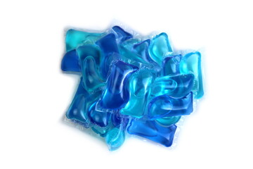 A lot of blue laundry capsules lie on a white background.