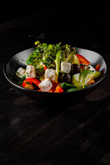 Fresh greek salad with tomato, cucumber, bel pepper, olives and feta cheese in black bowl