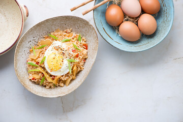 Korean kimchi fried rice on a light-beige marble background, horizontal shot with space, above view