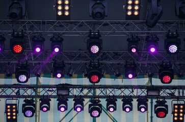 Concert lighting mounted on rack above the stage. High bar with professional LED spotlights and flood light projectors