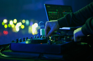 DJ playing electronic music set on party in night club. Close up photo of disc jockey mixing...
