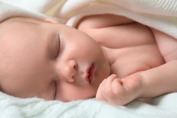 Cute newborn baby sleeping on white blanket, closeup
