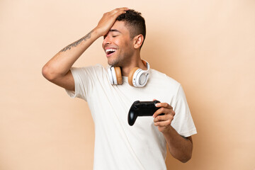 Fototapeta na wymiar Young Brazilian man playing with a video game controller isolated on beige background has realized something and intending the solution